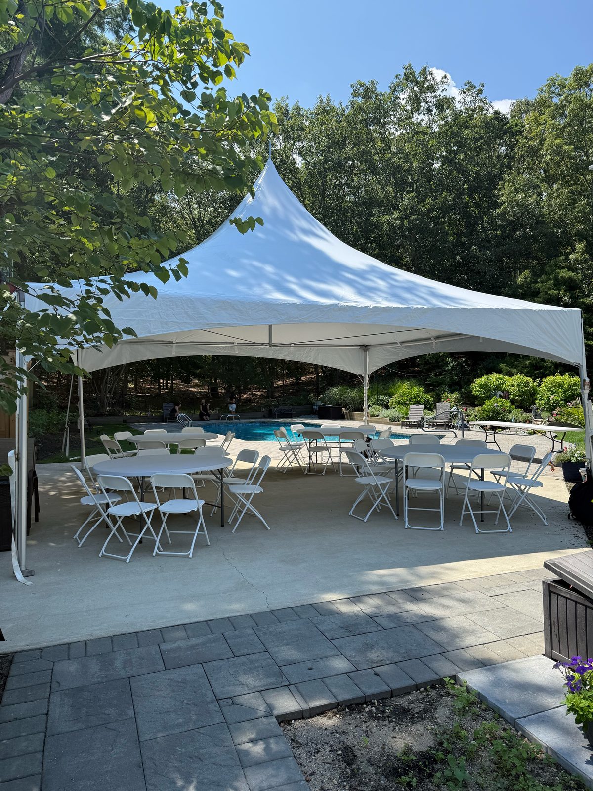 20x20 high peak tent on a sunny pool patio with round tables and white folding chairs